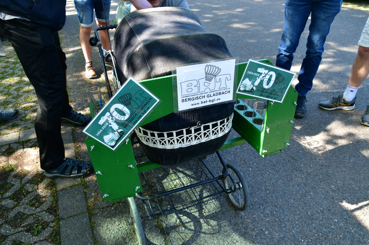Detailansicht eines mit Plakaten und Aufklebern verzierten Kinderwagens auf einem Gehweg.