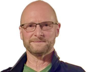 Ein Mann mit Brille und kurz geschorenem Kopf trägt ein grünes T-Shirt und hält einen Pokal in der Hand.