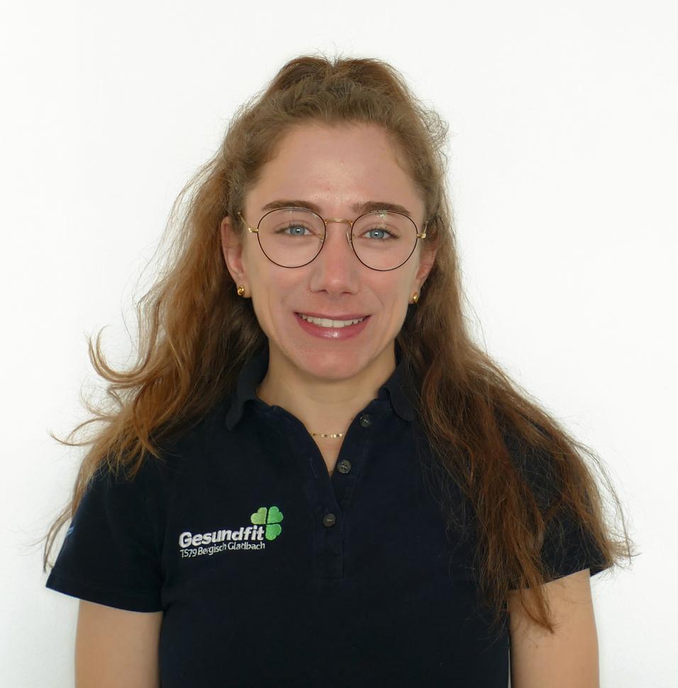 Porträt einer jungen Frau mit Brille, langem, lockigem Haar und schwarzem Poloshirt vor weißem Hintergrund.