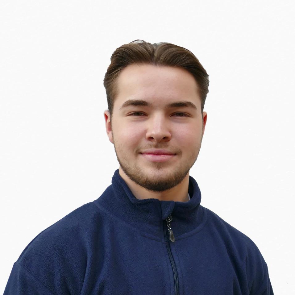 Porträt eines jungen Mannes in blauer Fleecejacke, lächelnd vor neutralem Hintergrund.