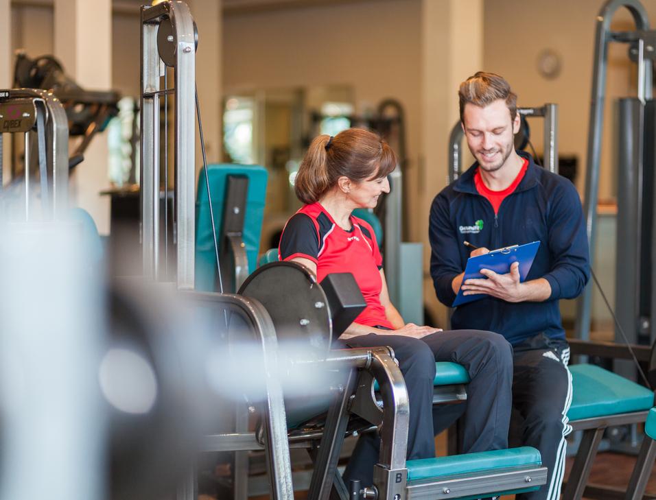 Ein Trainer berät eine Frau am Fitnessgerät in einem modernen Fitnessstudio.