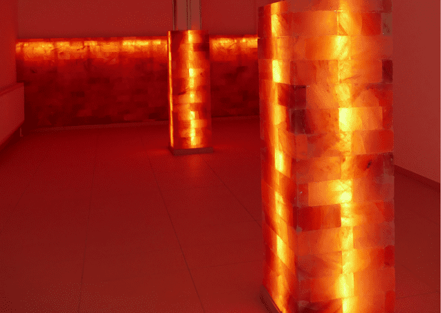 R&auml;ume mit leuchtenden S&auml;ulen aus Salzkristallen in warmen Oranget&ouml;nen auf einem hellen Boden.