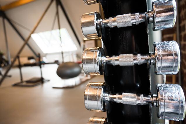 Nahaufnahme von mehreren chromierten Hanteln an einem Ständer in einem modernen Fitnessstudio.